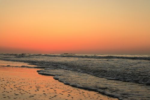 Free A serene sunrise at Hilton Head Island beach with gentle waves and an orange sky. Stock Photo