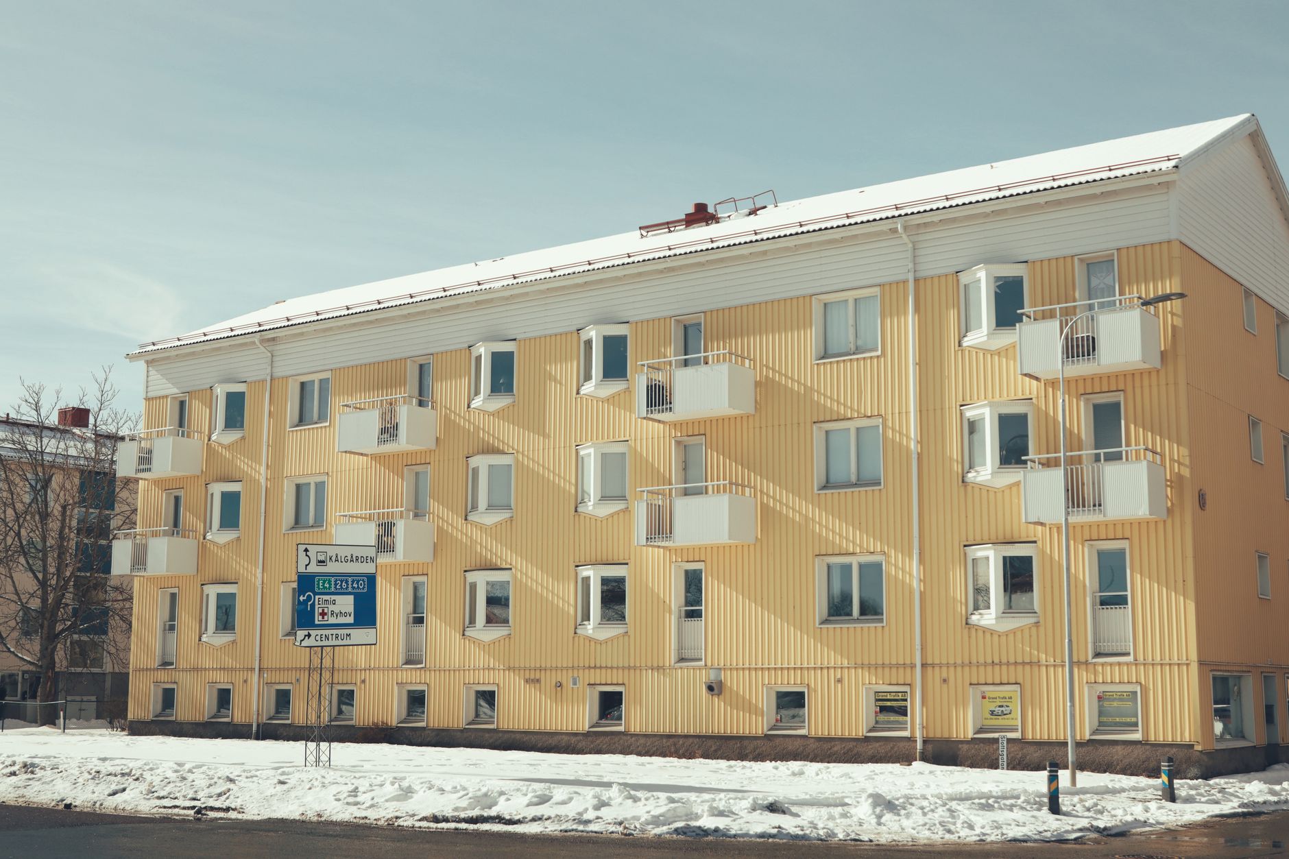 Yellow apartment building with balconies in snowy Jönköping, Sweden, during winter.