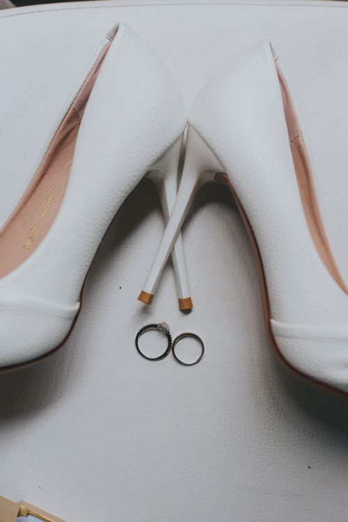 Free Sophisticated white high heels paired with wedding rings on a chic backdrop. Stock Photo