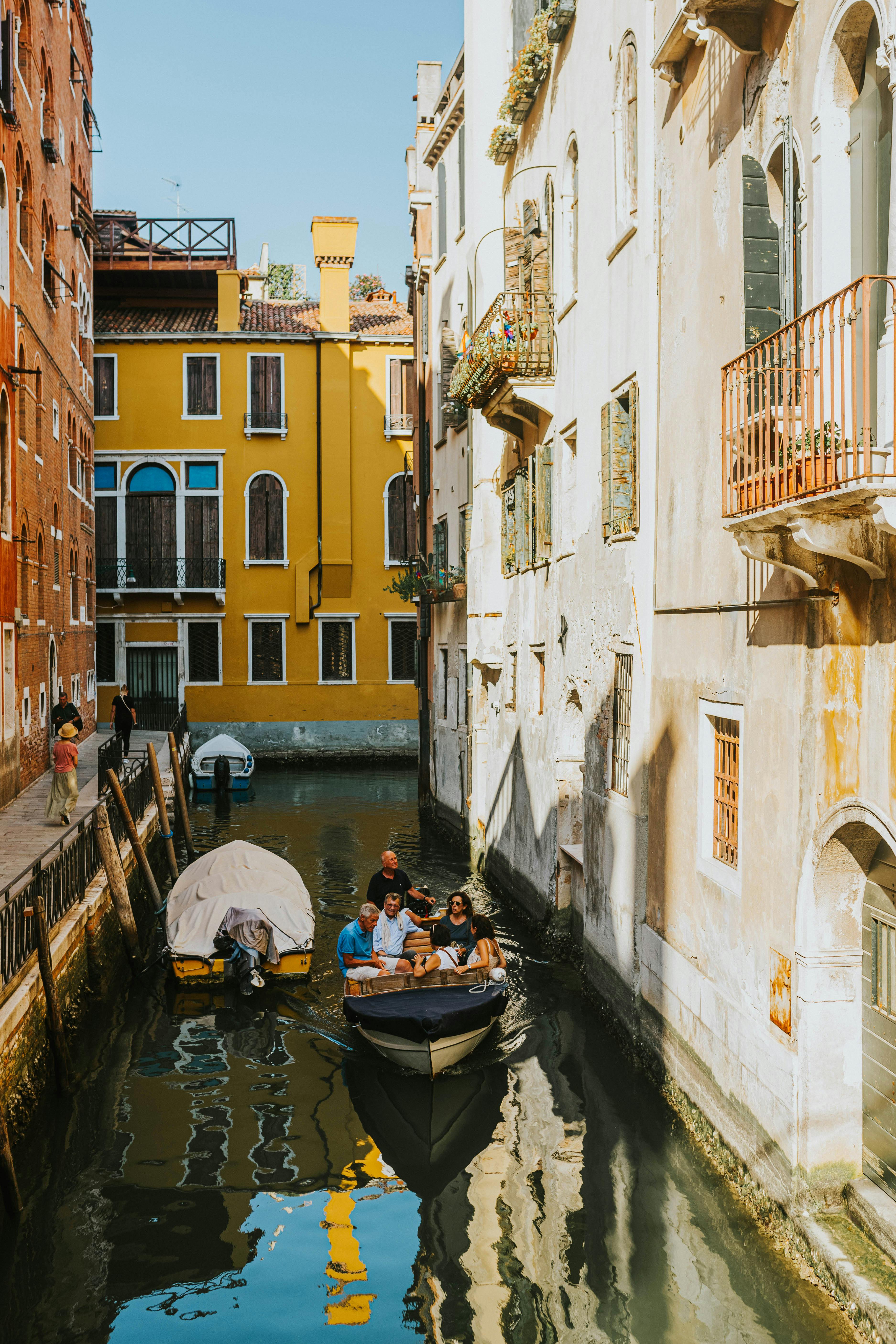 Tourists enjoying a gondola ride through a picturesque Venetian canal.