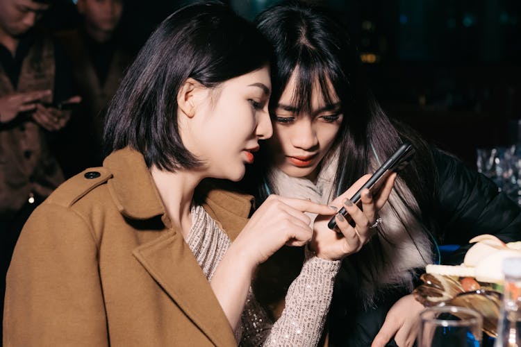 Women Looking At Phone At Party