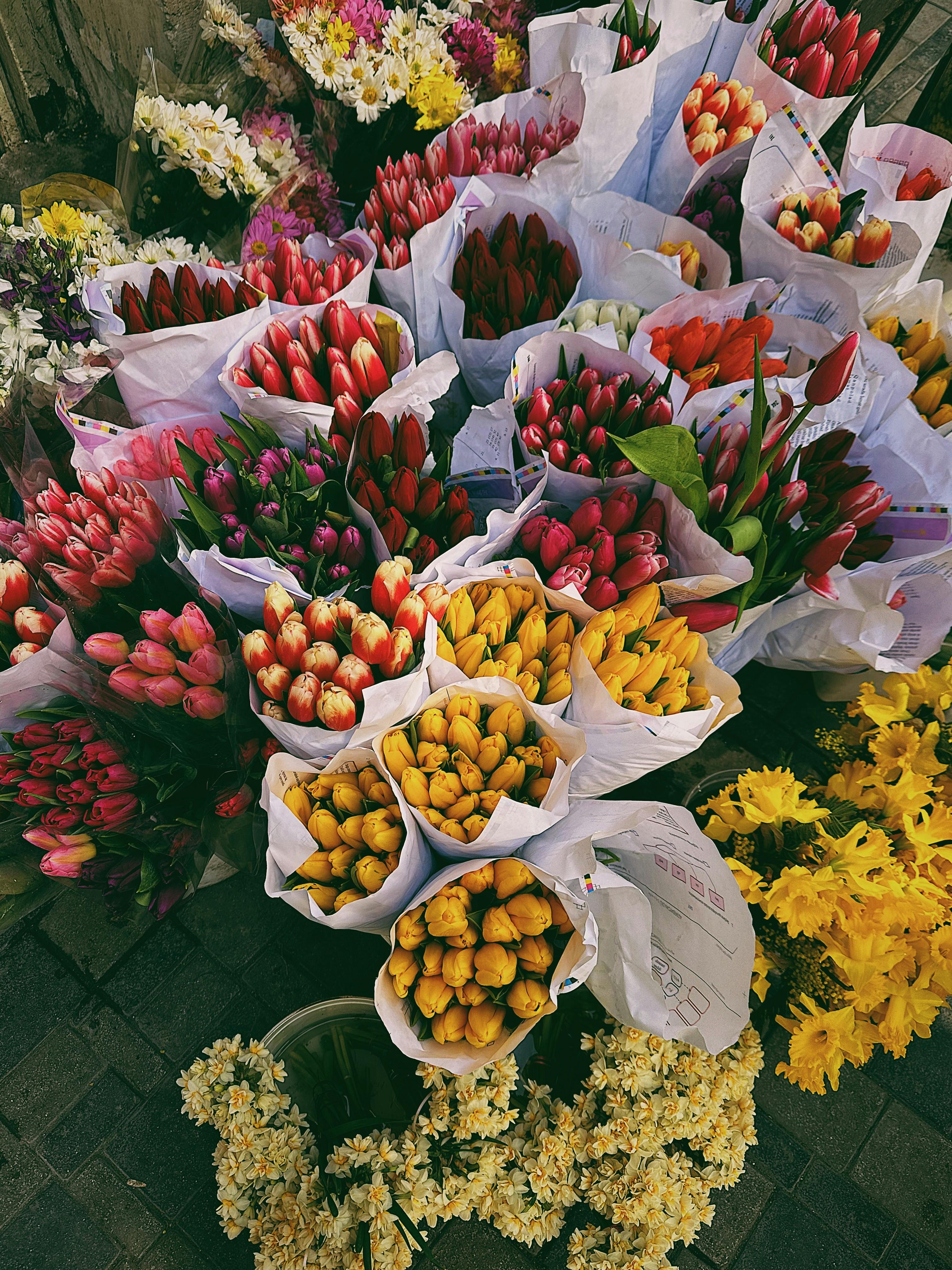 Colorful tulips and flowers arranged in bundles at an outdoor market, showcasing spring's vibrant beauty.