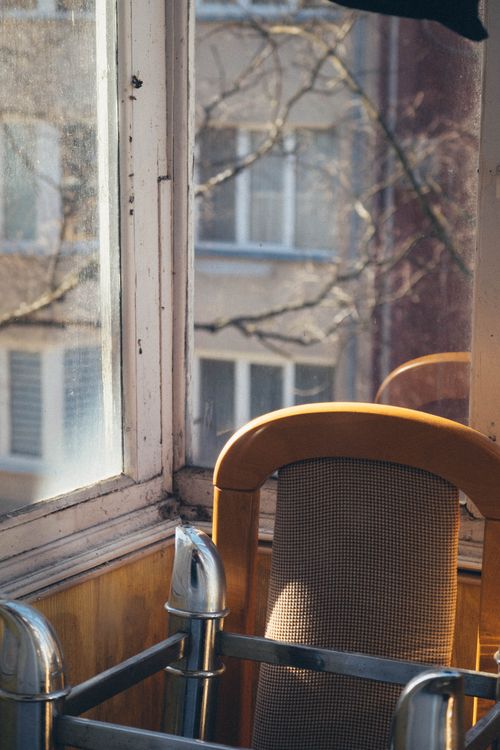 Free Sunlit urban interior with a stacked chair near old windows. A glimpse of city life. Stock Photo