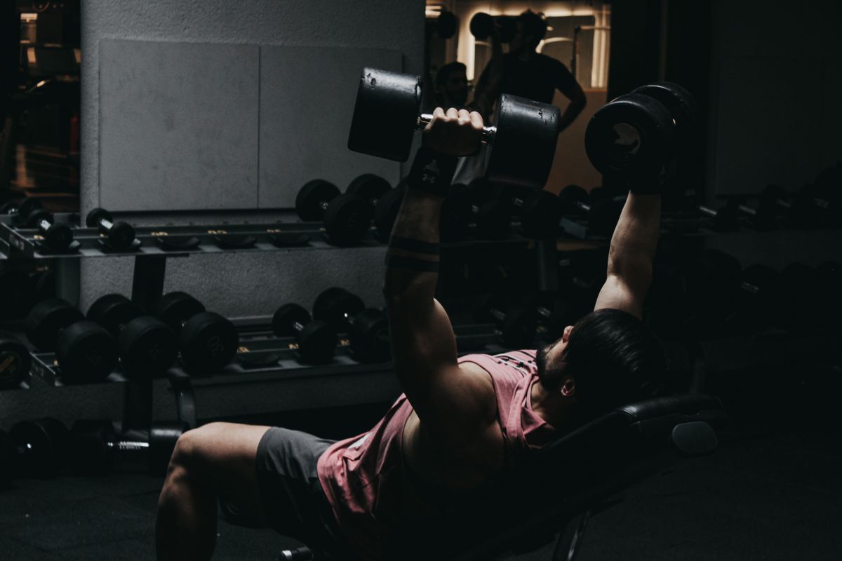 Athlete performing a dumbbell bench press, elbows tucked at a controlled angle