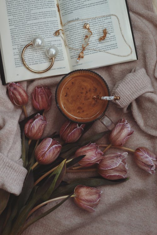 Blooming Tulips, a Glass of Coffee and Jewelry Lying on an Opened Book