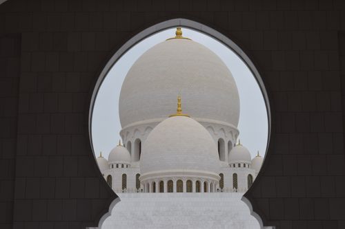 Free A stunning view of Sheikh Zayed Grand Mosque in Abu Dhabi through an archway, highlighting its dome and architectural beauty. Stock Photo
