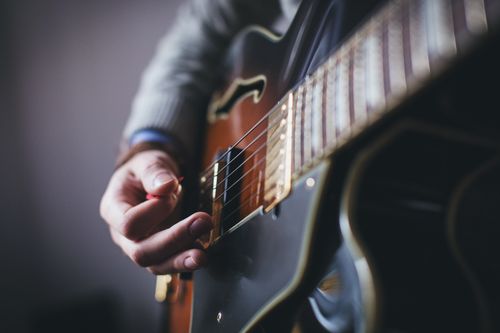 Free A detailed shot of a musician's hand strumming an electric guitar. Stock Photo