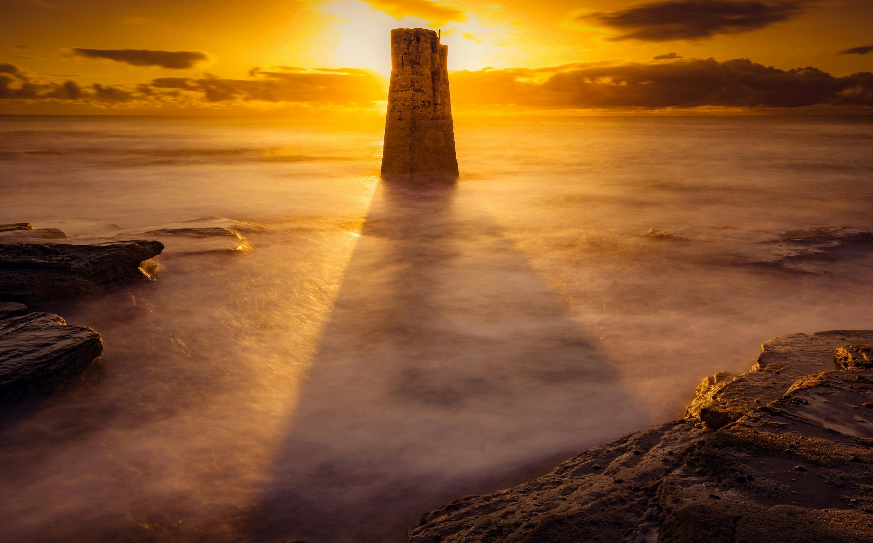 雄伟的日落映照着海洋，阳光投射出戏剧性的轮廓和阴影