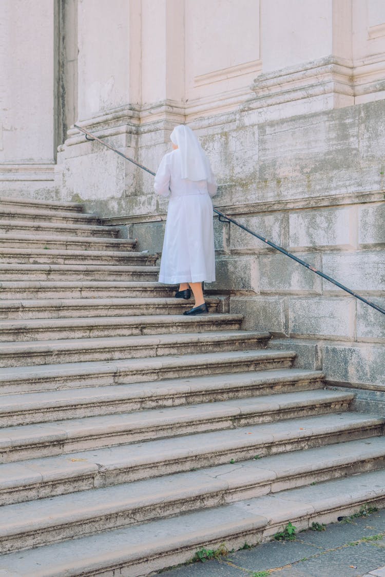 Nun Walking Stairs To Old Cathedral