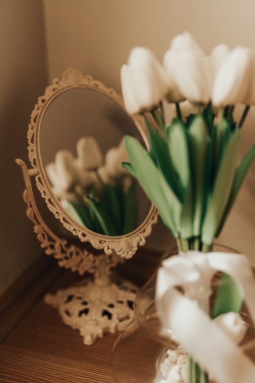Free A bouquet of white tulips with a decorative mirror on a vintage wooden desk, creating a romantic setting. Stock Photo