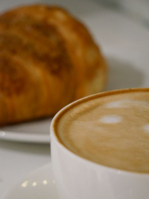 Free Close-up of a steaming cappuccino and fresh croissant on a plate, perfect breakfast setting. Stock Photo