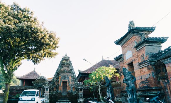 A serene view of a traditional Balinese temple surrounded by trees and architectural elements.