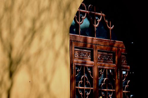 Free Close-up of an ornate wooden door with intricate carvings and shadows on a wall. Stock Photo