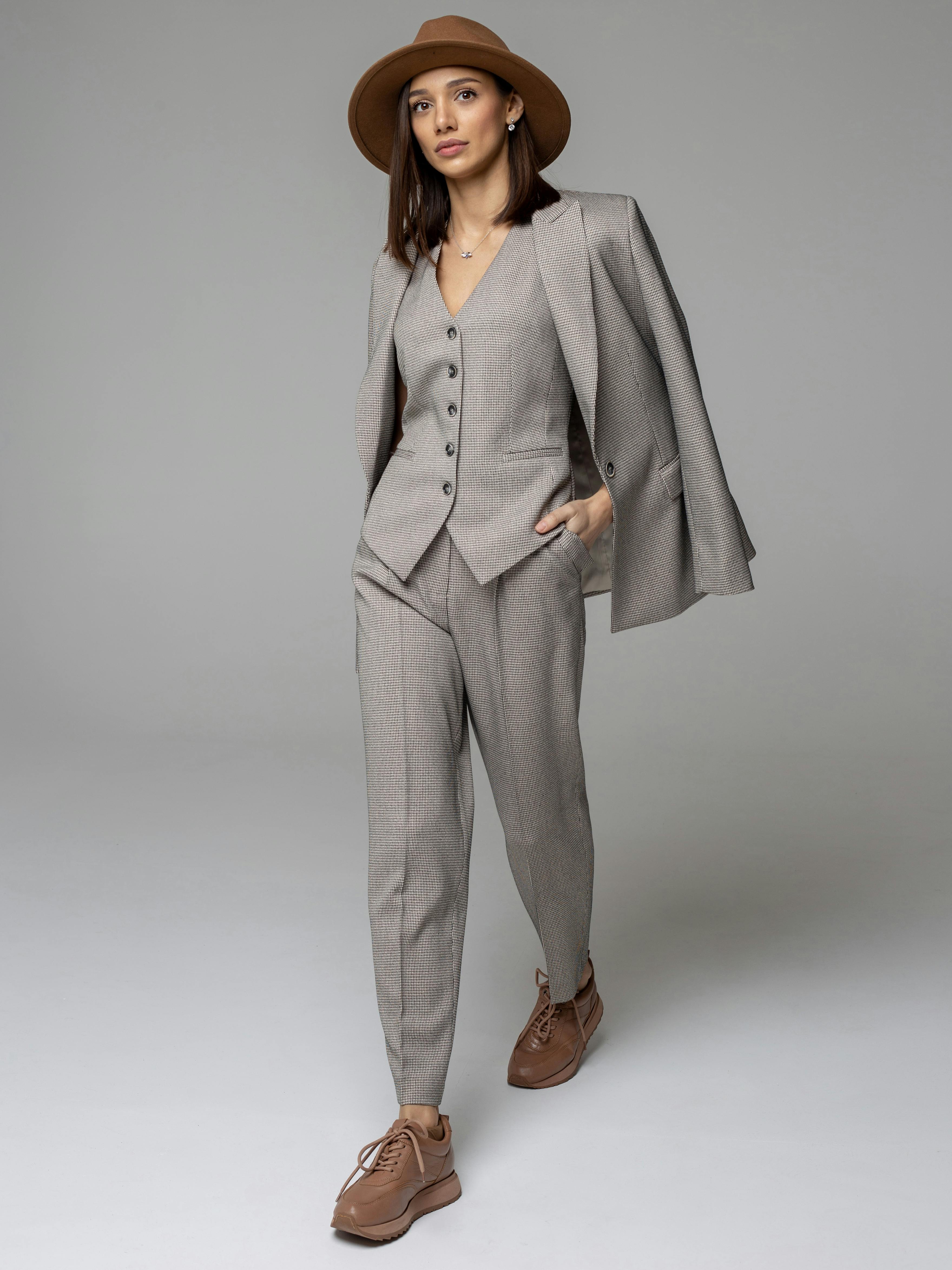 Stylish woman in a tailored gray suit and hat striking a confident pose.