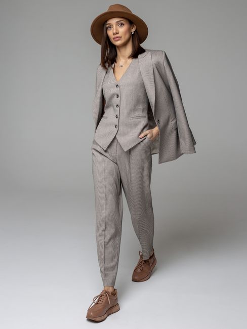 Stylish woman in a tailored gray suit and hat striking a confident pose.