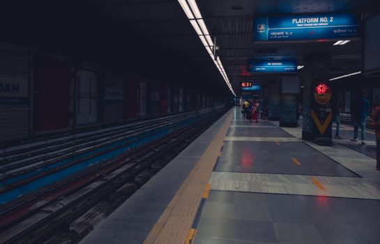 A dimly lit metro station platform with passengers waiting, showcasing urban public transportation.