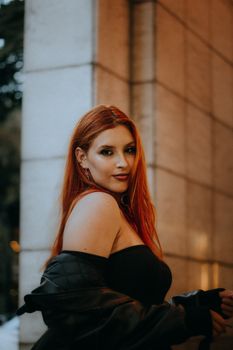 Stylish redhead woman with a confident pose in an elegant urban setting.