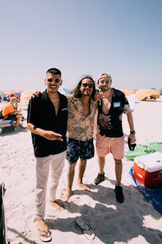 Three friends smiling and posing on a sunny beach day, enjoying their time together.