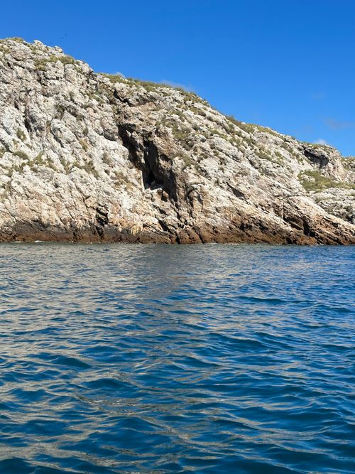 Free A clear sunny day highlights the rocky coastal cliffs and shimmering blue sea. Stock Photo