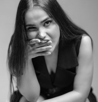 Grayscale portrait of a woman posing with a mysterious expression in a studio.