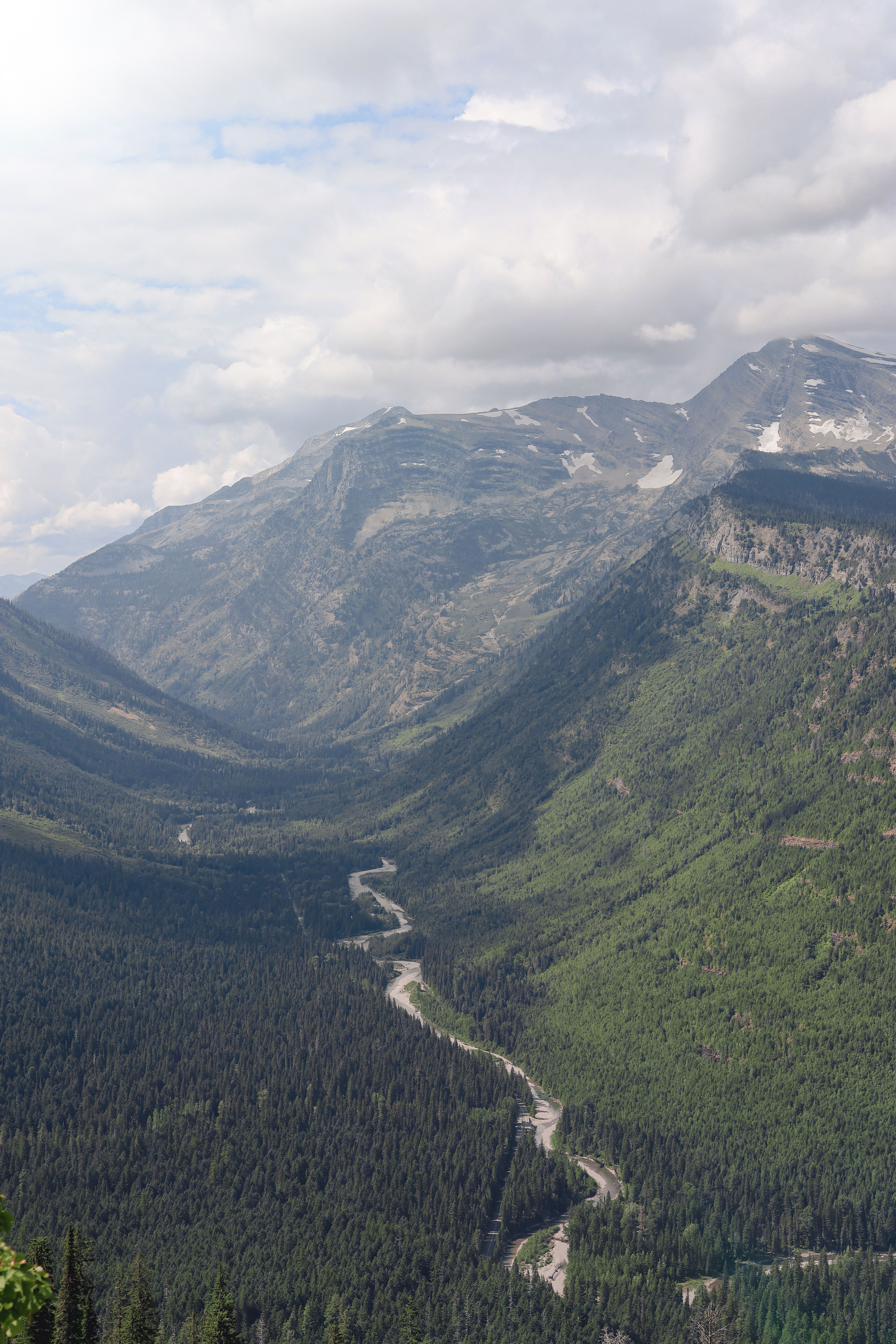 Shuttle bus parked near a mountain overlook in Glacier National Park with alpine peaks in the background