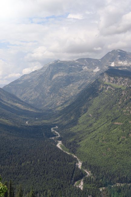 Shuttle bus parked near a mountain overlook in Glacier National Park with alpine peaks in the background