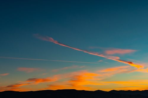 Free A stunning sunset with colorful clouds over silhouetted mountains, creating a serene landscape. Stock Photo
