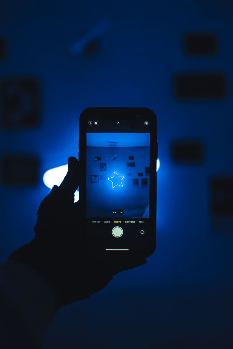 A person holding a smartphone displaying a glowing dark screen in a dimly lit room, suggesting a suspenseful social media moment