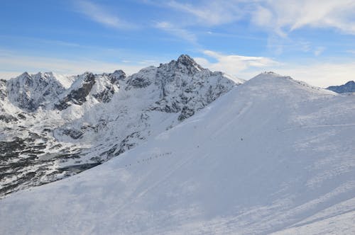 무료 파란과 백색 하늘 아래 눈 덮힌 산 스톡 사진