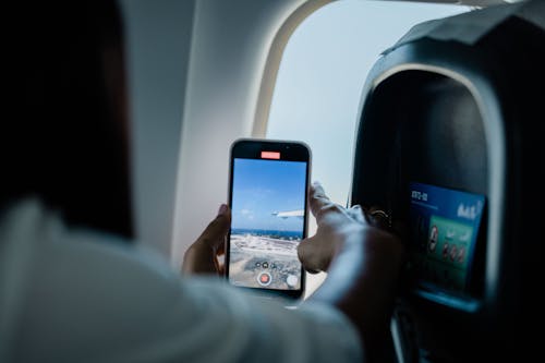 Close-up of a Woman Recording a Video of the View from an Airplane Window