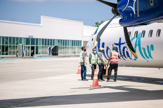 Ground crew in reflective vests preparing an airplane for departure at a sunny airport.