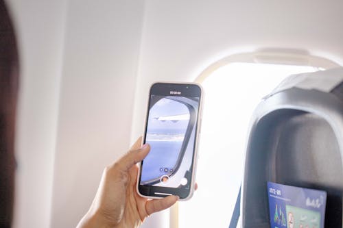 Close-up of a Man Recording a Video of the View from an Airplane Window 