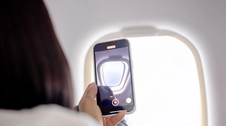 Passenger filming the view through an airplane window on a smartphone