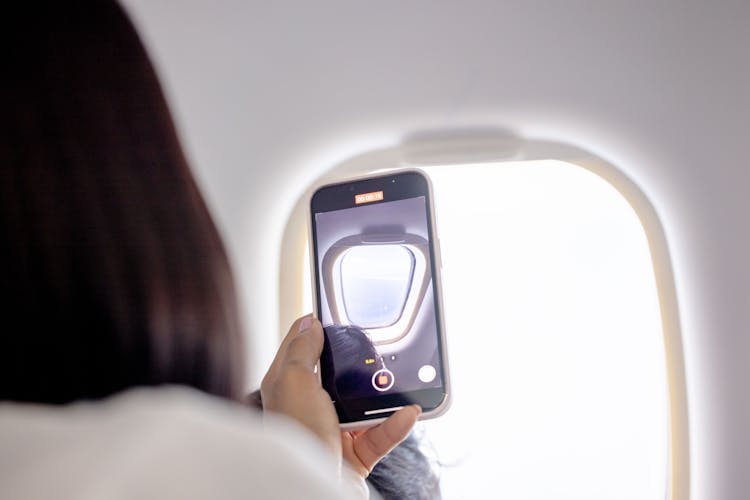 Woman Recording Video Through Airplane Window