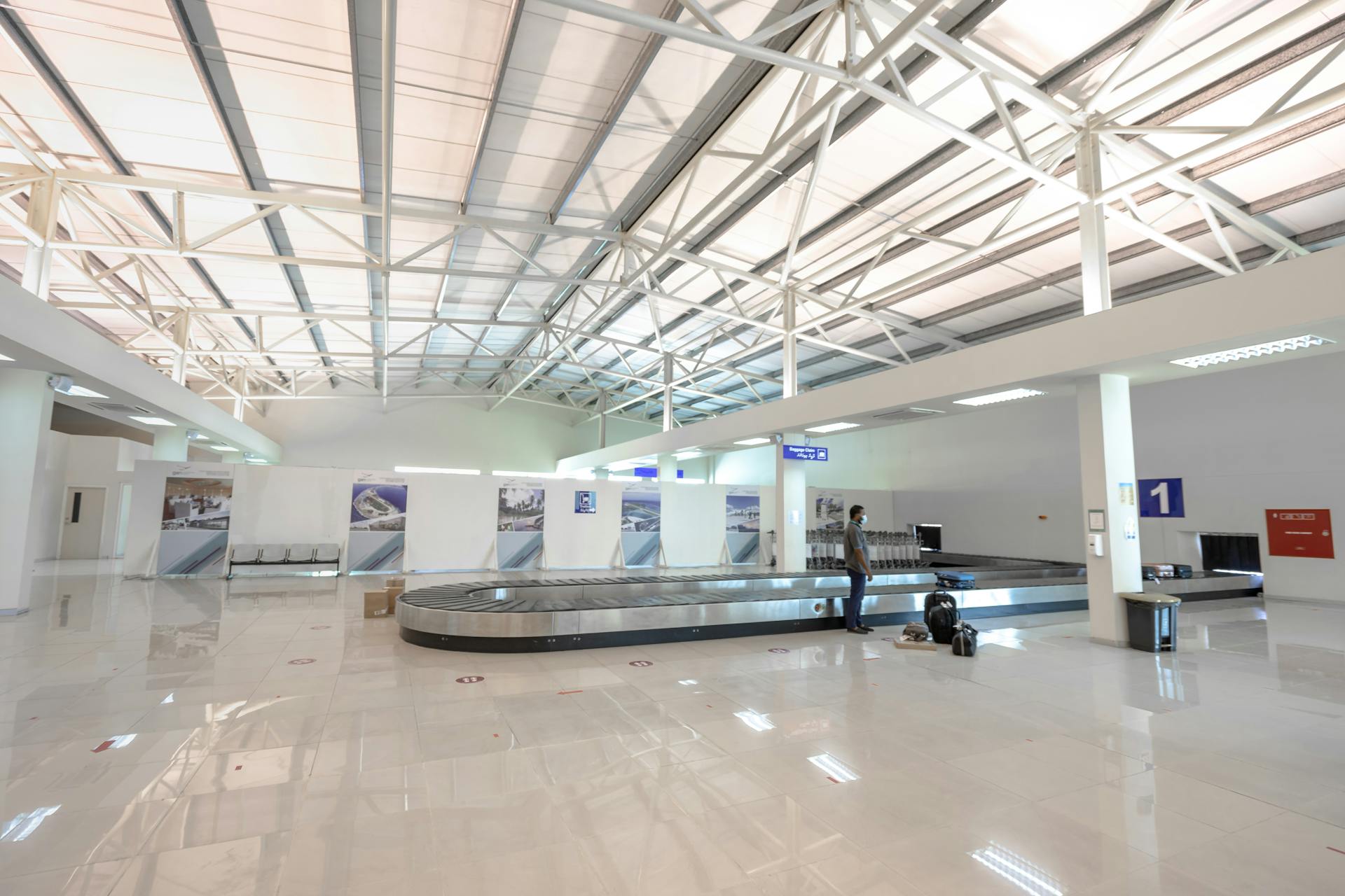 A modern and empty airport baggage claim area with a traveler waiting.