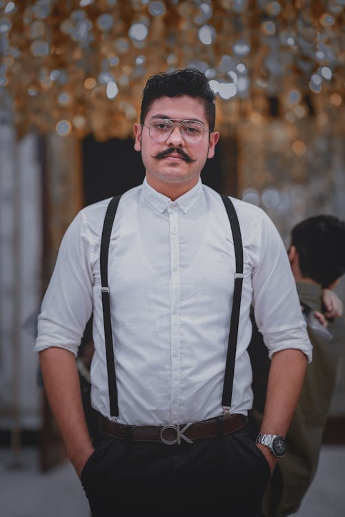 Elegant Man with Mustache and Eyeglasses, Wearing a White Shirt and Holding Hands in Pockets 