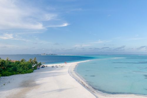 Free Aerial view of a serene tropical beach with white sand and clear azure waters in Guraidhoo, Maldives. Stock Photo