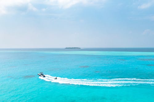 Aerial View of a Motorboat on a Turquoise Ocean and an Island in Distance 