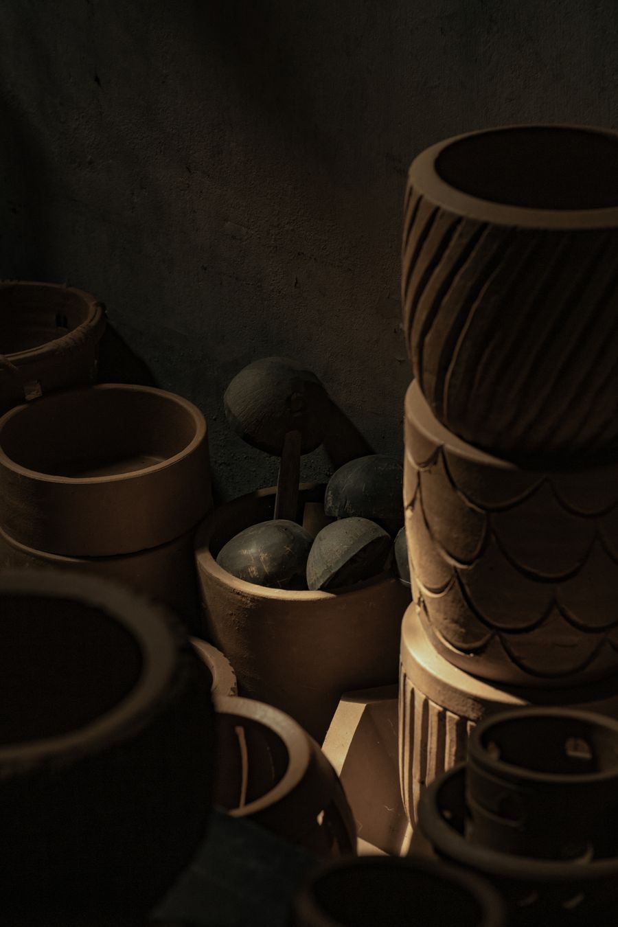 Unglazed vessels stacked in a dim workshop corner, photo by Melbin Jacob on Pexels