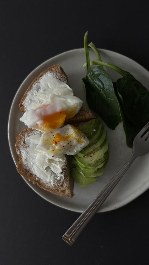 Free Delicious avocado toast topped with a fried egg and fresh spinach on a plate. Stock Photo