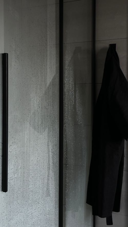 Free Black jacket hanging in a minimalist bathroom with glass shower door. Stock Photo