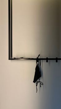 A simple black mask hanging in a minimalist interior space.