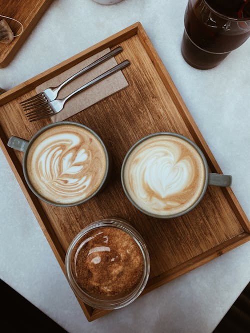 Cups with Cappuccinos on Wooden Board on Table