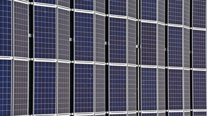 close-up of dark solar cells and blue speckled solar cells side by side on a rooftop