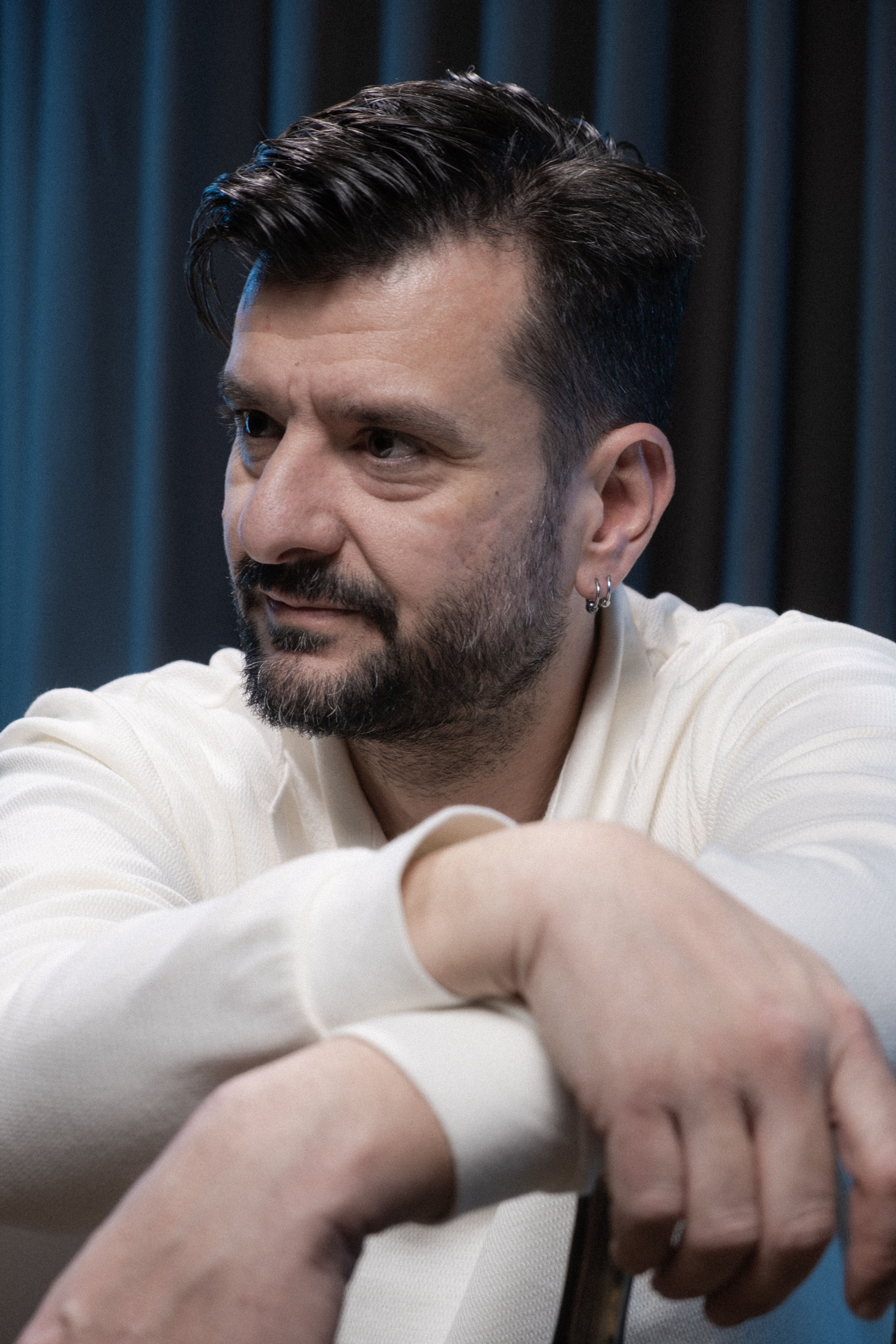 Portrait of a fashionable man with a beard, elegantly posing indoors with thoughtful expression.