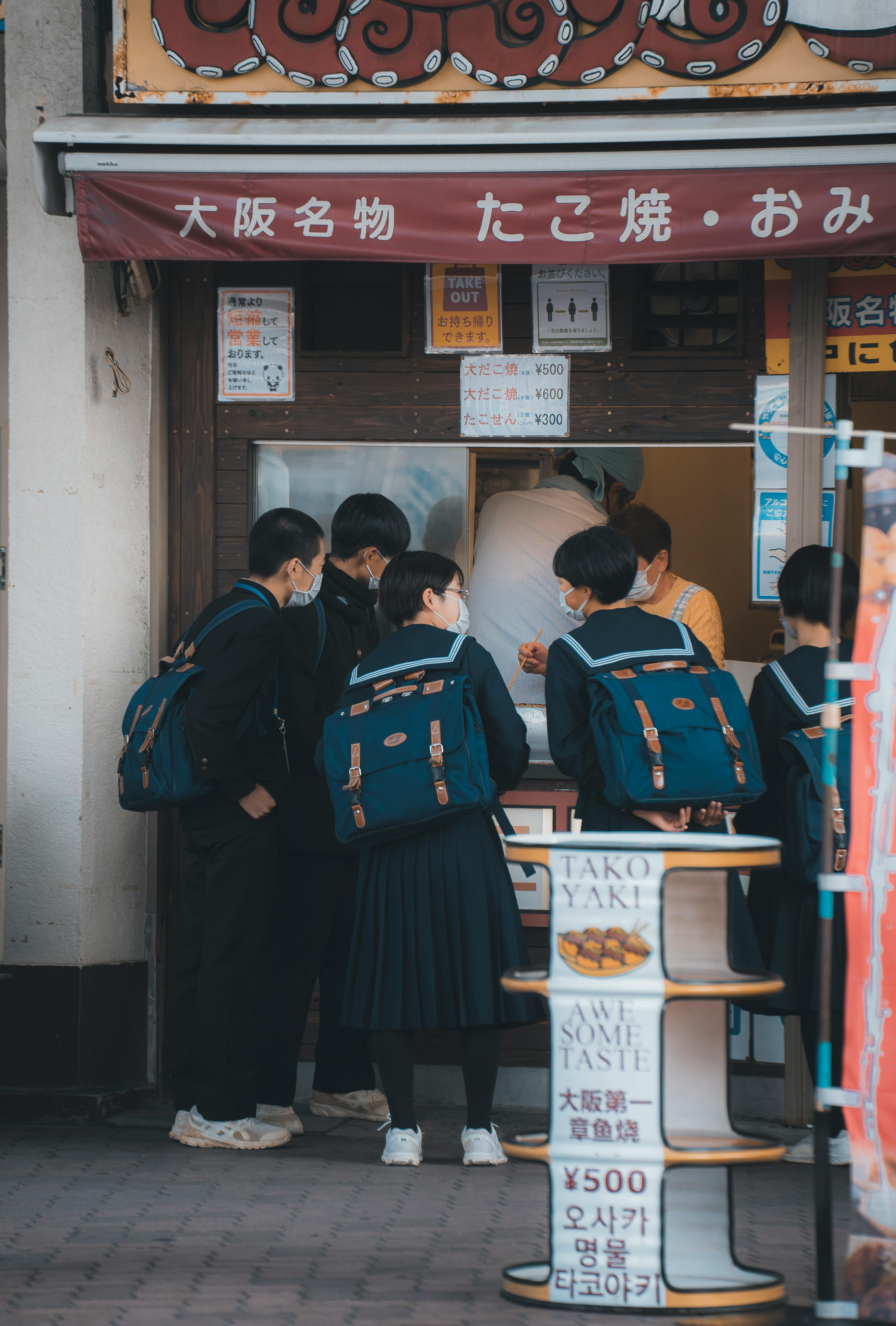 schoolchildren with backpacks near street shop