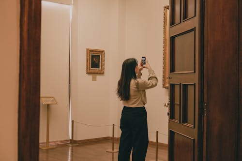 A Woman Taking a Photo in an Art Gallery