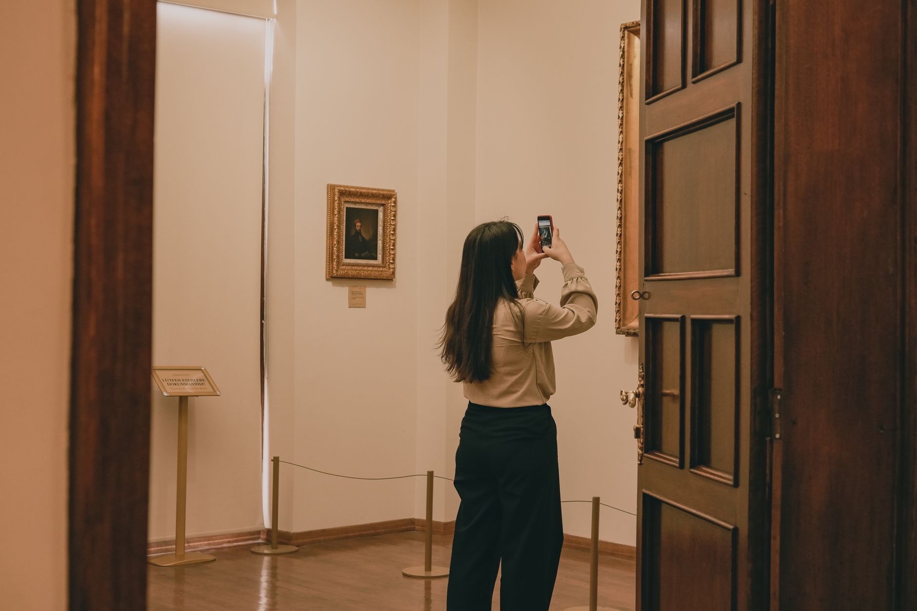 Woman capturing artwork with phone in a tranquil museum setting.