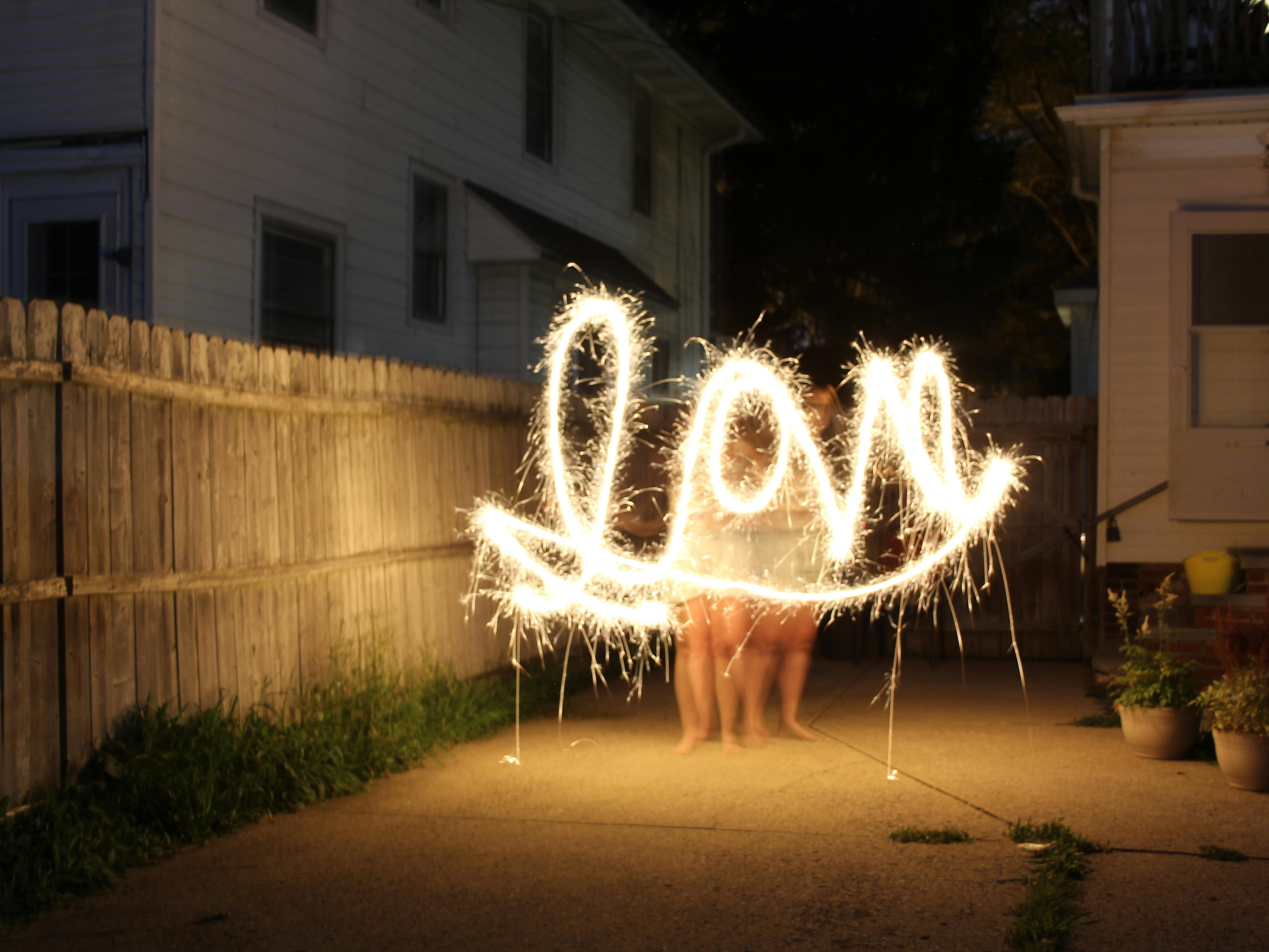 Captivating nighttime sparkler art spelling 'love' in a cozy backyard setting.
