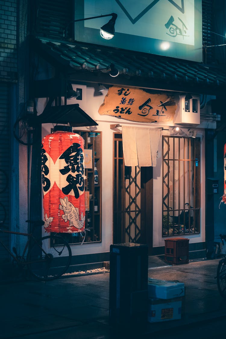 Lantern Glowing In Front Of A Closed Store At Night